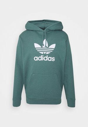 Sudadera con capucha verde de Adidas con logo trébol blanco y bolsillo de canguro, con capucha ajustable con cordón.