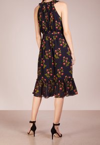Blumenkleid mit schwarzem Hintergrund, gerafftem Saum, Halterneck und tailliertem Schnitt. Akzentuiert mit kleinen pinken und grünen Blumen.