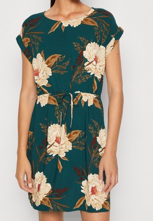 Robe bleu sarcelle longueur genoux avec un grand imprimé floral crème et marron, manches courtes retroussées, col rond et ceinture nouée à la taille.