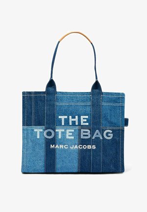 Denim patchwork tote bag med to hanke, hvidt fed tekst "THE TOTE BAG" og mindre "MARC JACOBS" på frontpanelet.