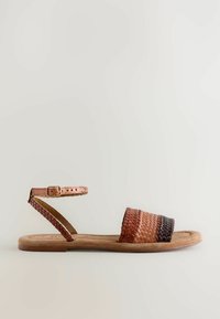 Sandalo in pelle intrecciata con tomaia incrociata in gradient brown, cinturino alla caviglia regolabile e suola piatta.