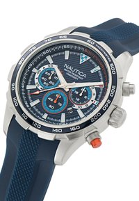 Reloj cronógrafo Nautica con correa de goma azul, caja plateada, esfera azul texturizada, tres subesferas azules y acento naranja en la corona.