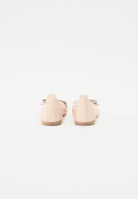 Chaussures en cuir beige avec un profil bas et un design matelassé texturé. Dotées d'un système de laçage et d'une semelle marron clair.