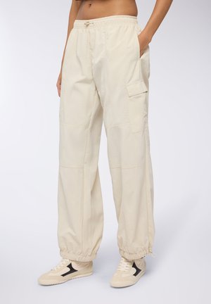 Pantaloni cargo beige con cintura elastica, tasche laterali e polsini elastici; realizzati in tessuto leggero con una texture liscia.