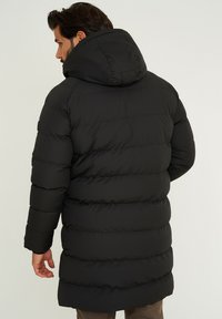 Black puffer jacket with a hood, featuring a quilted design, long length, and a smooth, shiny texture. The back shows horizontal seams.