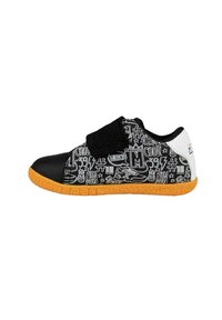 Zapatilla de tela negra con un upper estampado que presenta gráficos en blanco, una correa de velcro negra y una suela de goma naranja.