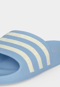 Sandale bleu clair à enfiler avec trois bandes blanches horizontales sur le dessus et semelle texturée.