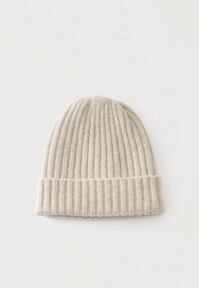 Bonnet d'hiver beige en tricot côtelé avec revers plié, posé à plat sur un fond blanc.