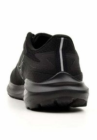 Zapatilla atlética negra con un upper de malla texturizada, un collar acolchado y detalles reflectantes en el talón, que cuenta con una suela acolchada.