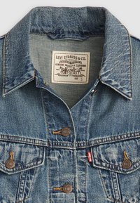 Veste en denim bleu Levi's avec boutons en métal, poches avant à rabat et une étiquette blanche indiquant le logo et la taille small.