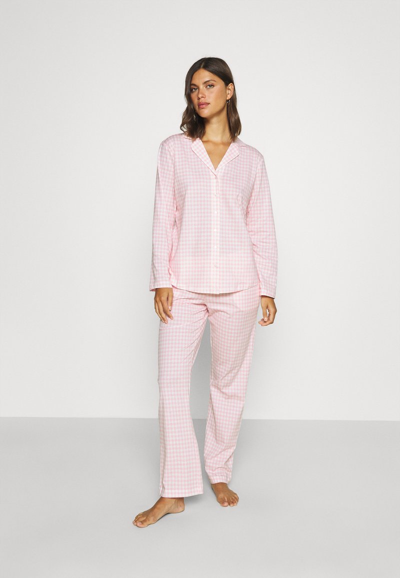 En rosa och vit rutigt pyjamas-set som består av en knapp-up skjorta med krage och långa ärmar, tillsammans med matchande rak ben-byxor.