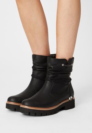 Bottines en cuir noir avec un tige décontractée, des accents de couture et des semelles en caoutchouc avec un motif texturé pour une meilleure adhérence.