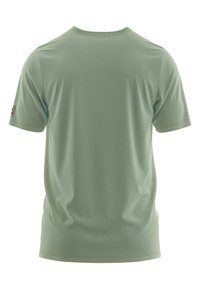 Camiseta de manga corta verde claro con cuello redondo, textura suave y dobladillos cosidos; presenta una pequeña etiqueta con el logotipo en el lado izquierdo.