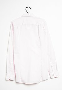Camisa de manga larga color rosa claro, mezcla de algodón, textura suave, puños con botones, forma rectangular, cuello de camisa, colgando de un gancho negro.
