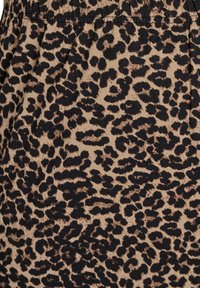 Tissu imprimé léopard avec un fond beige et des taches noires, présentant une texture douce et une taille élastiquée.