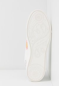 Semelle de chaussure blanche avec des motifs floraux et cachemire complexes en relief, affichant le nom de la marque "ALDO" au centre.
