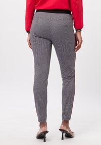 Leggings à motifs noir et blanc avec une coupe slim, dotés d'une bande latérale rouge, d'une taille élastique et d'une texture lisse.