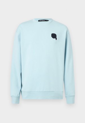 Ανοιχτό μπλε μακρυμάνικο φούτερ με στρογγυλή λαιμόκοψη, με ένα μικρό μαύρο γραφικό έμβλημα στο αριστερό στήθος και ριμπ μανσέτες και τελείωμα.