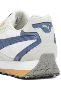 Weiße Sneaker mit blauen Lederakzenten, grauen Wildlederdetails und einer Gummisohle mit strukturiertem Muster. Puma-Logo in Gelb an der Ferse.