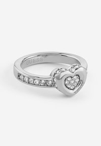 Anello in argento con un design a forma di cuore, caratterizzato da cristalli trasparenti incastonati e una finitura lucida, impreziosito con la scritta "GUESS" sulla fascia.