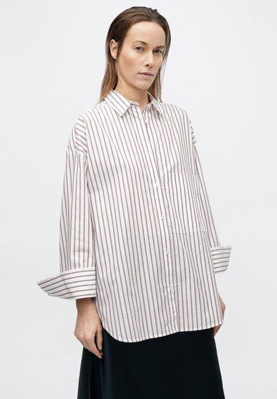 Biela košeľa na gombíky s červenými zvislými pruhmi, s golierom, dlhými rukávmi so zrolovanými manžetami a náprsným vreckom.