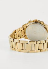 Montre en acier inoxydable doré avec un bracelet à maillons, un boîtier rond et plusieurs fonctions de chronographe à bouton-poussoir. Finition métallique lisse.