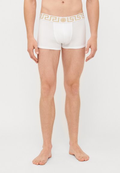 Boxeri albi din bumbac, cu un brâu cu model în cheie grecească de culoare aurie, având o croială strânsă și un design minimalist.