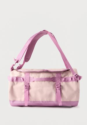 Rektangulær lys rosa duffelbag med justerbar skulderstropp, toppglidelås og flere håndtak på en ensfarget bakgrunn.