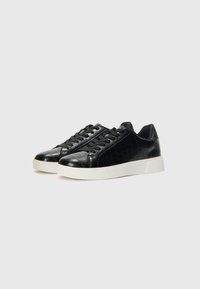 Black leather sneakers with a crocodile skin texture, featuring a white rubber sole and black laces, offering a rounded toe design.