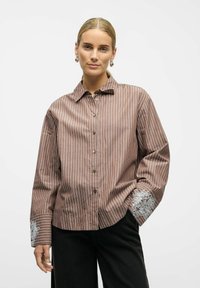 Brown and white striped shirt with a collar, long sleeves, and floral embroidery on cuffs. Button closure and relaxed fit.