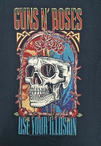 Černé tričko s barevným potiskem lebky, které je obtočené ostnatým drátem a růžemi; text zní "GUNS N' ROSES" a "USE YOUR ILLUSION."