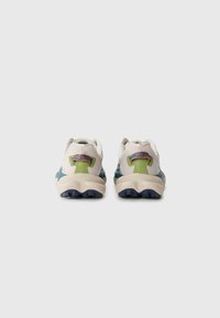 Schoenen met een crèmekleurige en groene bovenkant, textuurdetail en een blauwe rubberen zool met uitgesproken grippatronen.
