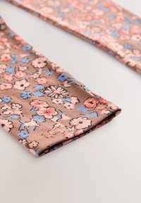 Brune blomstrede leggings med rosa og blå blomsterprint, lavet af blødt stof, med en konisk pasform og en pæn opsmøget kant.