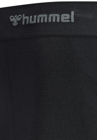 Svarta atletiska leggings med en texturerad design och en bred midjeband som har "hummel"-logotypen i ljusgrått.