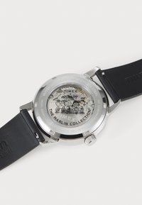 Back of Timex watch from The Marlin Collection with visible automatic movement and Peanuts characters printed on the case.
