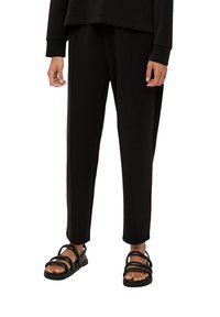 Zwarte sweatpants met een relaxte pasvorm en verticale stiksels. Gecombineerd met zwarte sandalen met bandjes en een gegroefde zool.