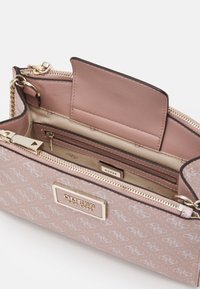 Borsa a tracolla rosa con motivo, caratterizzata da un logo dorato, una cerniera, un interno foderato e più scomparti. Texture liscia e catena della tracolla visibile.