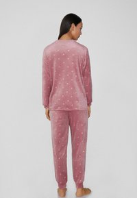 Rosa Velours-Pyjama-Set mit Punkten; langärmeliges Oberteil und passende Hose; weiche Textur; gerippte Bündchen an Beinen und Ärmeln.