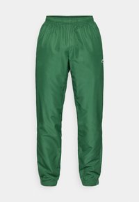 Pantalones deportivos verdes con cinturilla elástica, tobillos ajustados y tejido liso y brillante. Detalle sutil del logo en la pierna.