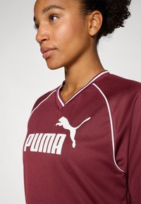 Maroon athletic jersey with a V-neck and white accents. Features the white Puma logo prominently on the front. Made of breathable material.