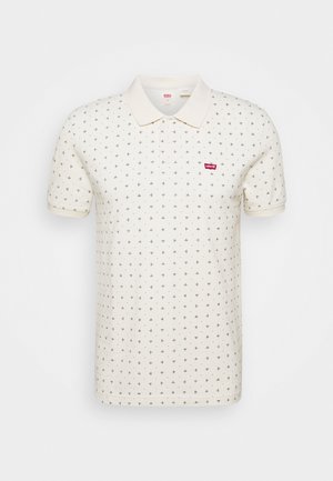 Crèmekleurig poloshirt met korte mouwen, klein zwart bladpatroon en rood Levi's-logo op de linkerborst.