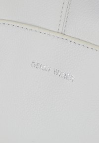 Biały materiał skórzany o teksturowanej powierzchni, z wytłoczonym logo "GERRY WEBER" w kolorze srebrnym. Czysty design z minimalnymi detalami szycia.