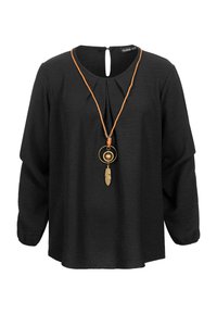 Black long-sleeve blouse with pleats at neckline and a keyhole back, accompanied by an orange cord necklace with gold circular pendant and feather.
