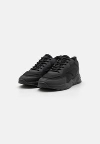 Black athletic shoes with a textured upper, prominent lacing system, padded collar, and a rubber sole featuring small traction details.