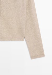 Beige stickad cardigan med långa ärmar, ribbade cuffs och nederkant. Mjuk textur med en enkel design, lämplig för lager-på-lager.
