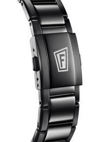 Montre en métal noir avec un large bracelet à maillons. Présente un cadran rectangulaire avec un logo "F" et une fermeture à bouton-poussoir. Texture lisse.