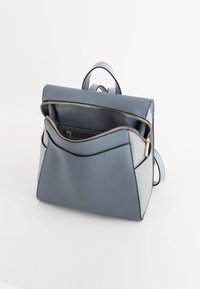 Rucsac din piele albastră cu un design structurat, dotat cu o închidere cu fermoar în partea de sus, buzunar frontal cu fermoar și un accent de culoare albastră deschisă.