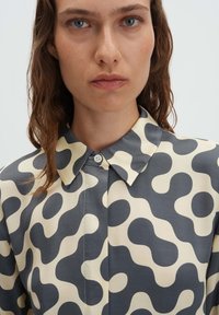 Button-up shirt with a grey and cream abstract pattern, featuring a standard collar and smooth texture.