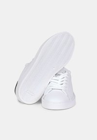 Sneaker bianche con una parte superiore in pelle liscia, punta rotonda e lacci piatti. Presenta una suola in gomma testurizzata con motivo a spina di pesce.