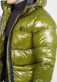Olivgrön puffjacka med glansig yta, med huva, zip-up stängning och broderad logga på bröstet.